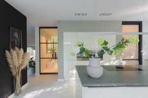 Stalen taatsdeur met slank zwart profiel die hal en woonkamer verbindt, met veel licht en een moderne, open uitstraling.