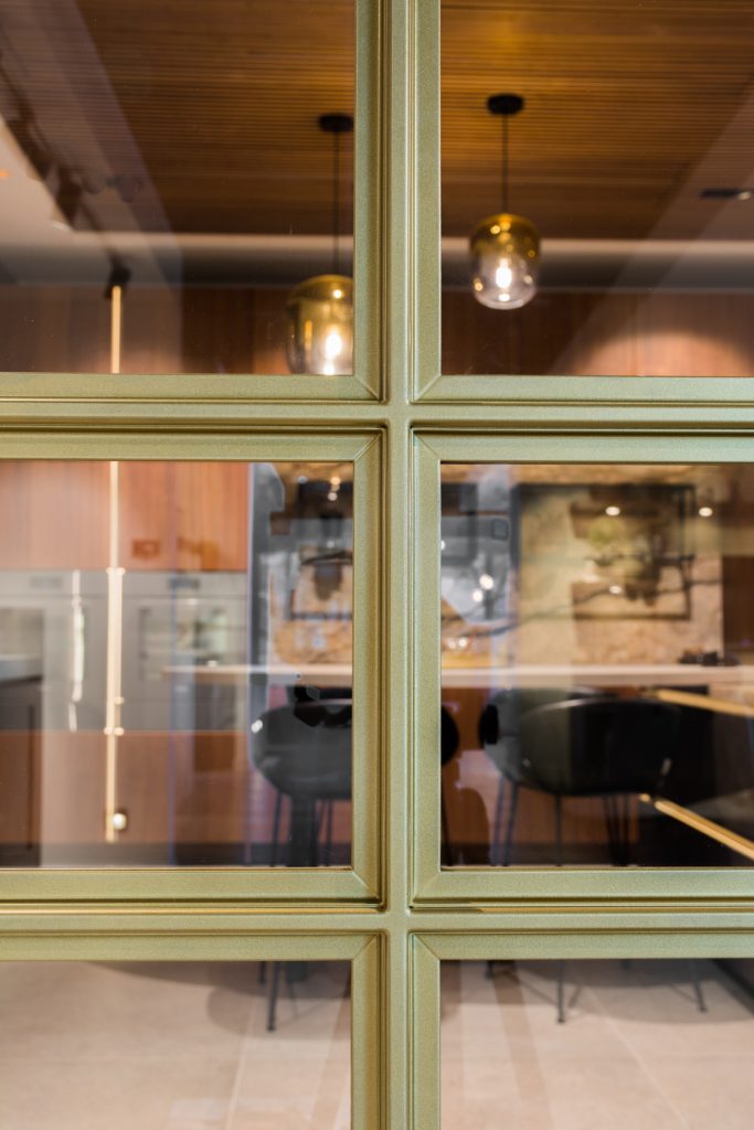 Stalen deur met luxe messing afwerking en glas, met verfijnde lijnen en een moderne, elegante uitstraling.
