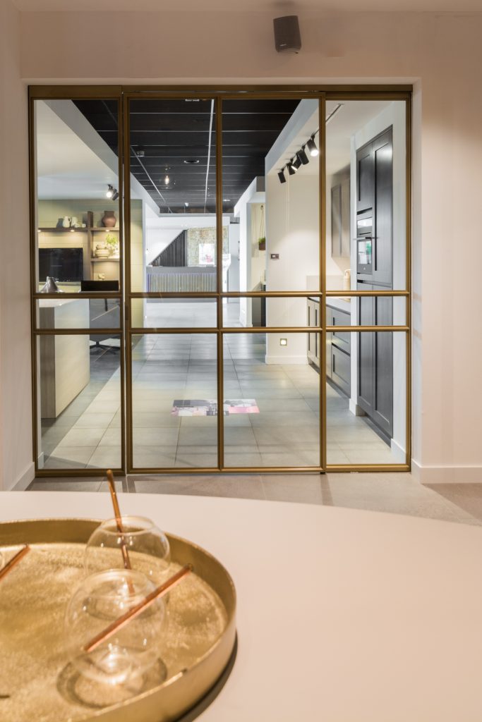 Stalen deur met messing afwerking bij Grando Keukens Zwaag, met glas en moderne, luxe uitstraling.
