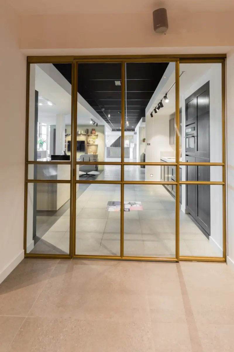 Stalen deur met messing afwerking bij Grando Keukens Zwaag, met glas en moderne, luxe uitstraling.