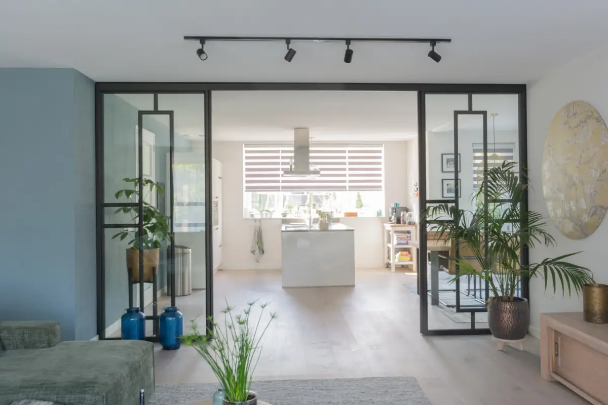 Stalen pui met schuifdeur als roomdivider tussen keuken en woonkamer