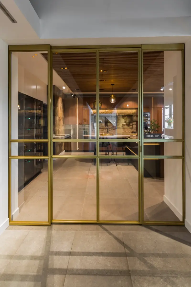 Stalen deur met messing afwerking bij Grando Keukens Zwaag, met glas en moderne, luxe uitstraling.