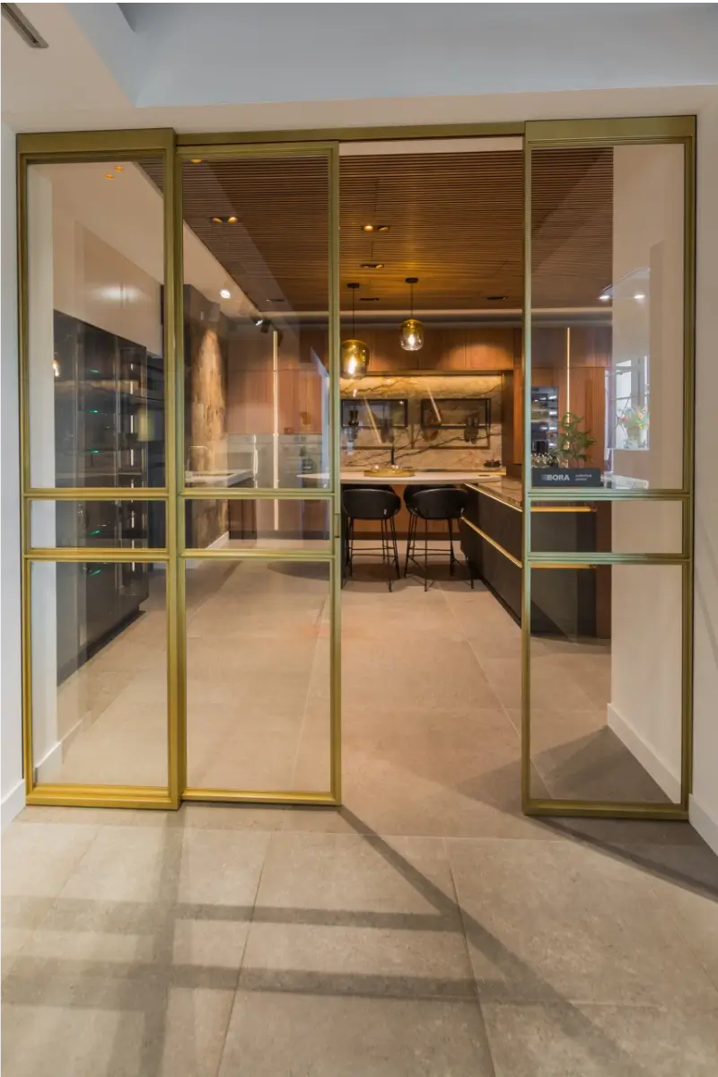 Stalen deur met messing afwerking bij Grando Keukens Zwaag, met glas en moderne, luxe uitstraling.