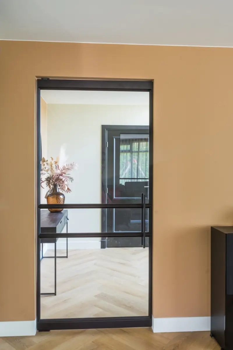 Taatsdeur en raampaneel in modern interieur. Deze deur is uitgevoerd in RAL 8022 in combinatie met grijs glas
