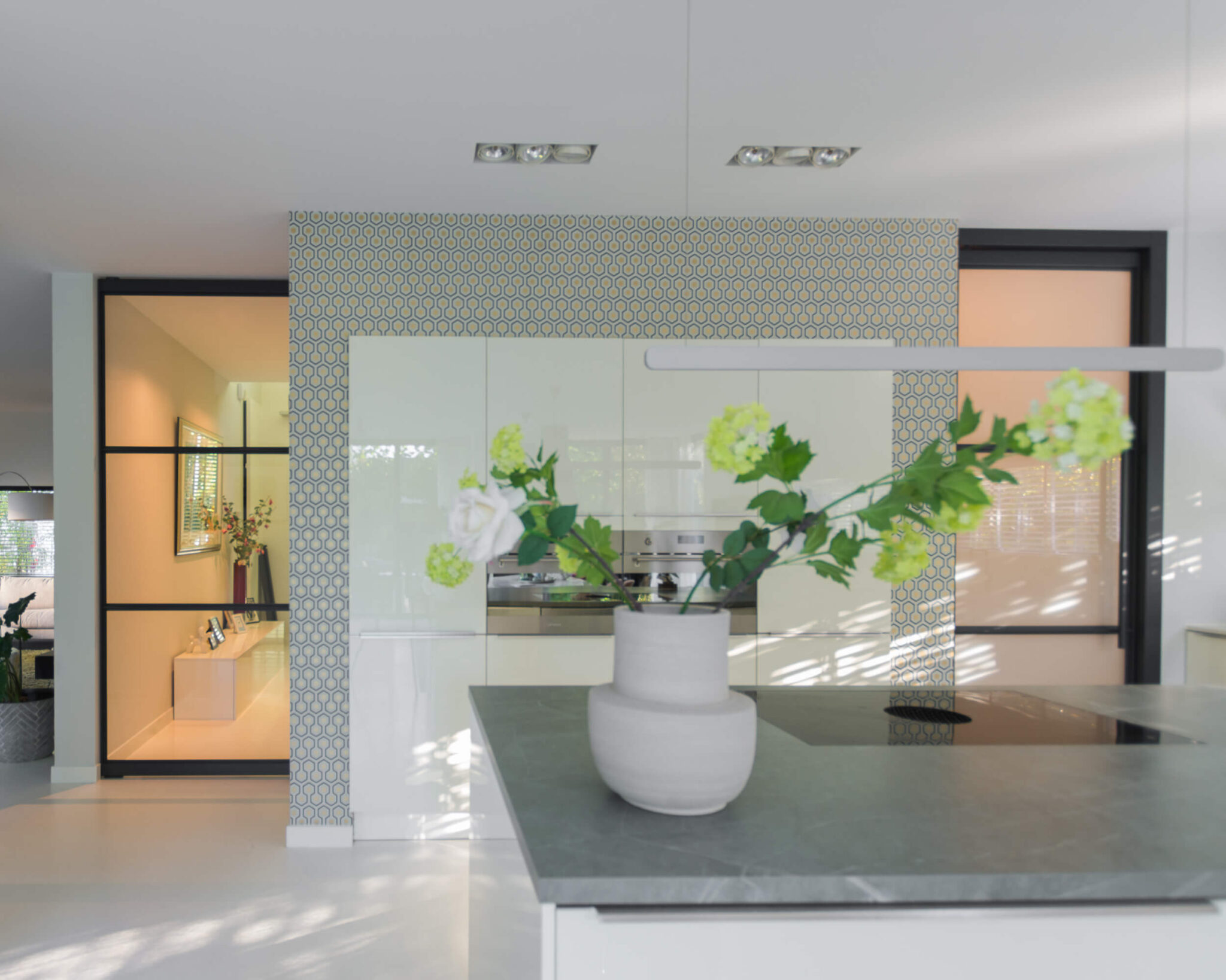 Stalen taatsdeur met slank zwart profiel die hal en woonkamer verbindt, met veel licht en een moderne, open uitstraling.