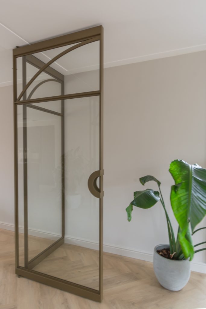 Exclusieve stalen taatsdeuren met boogdetails in een licht beige interieur.