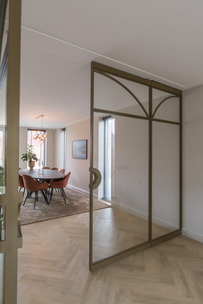 Exclusieve stalen taatsdeuren met boogdetails in een licht beige interieur.