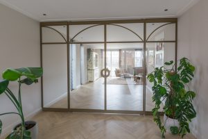 Exclusieve stalen taatsdeuren met boogdetails in een licht beige interieur.