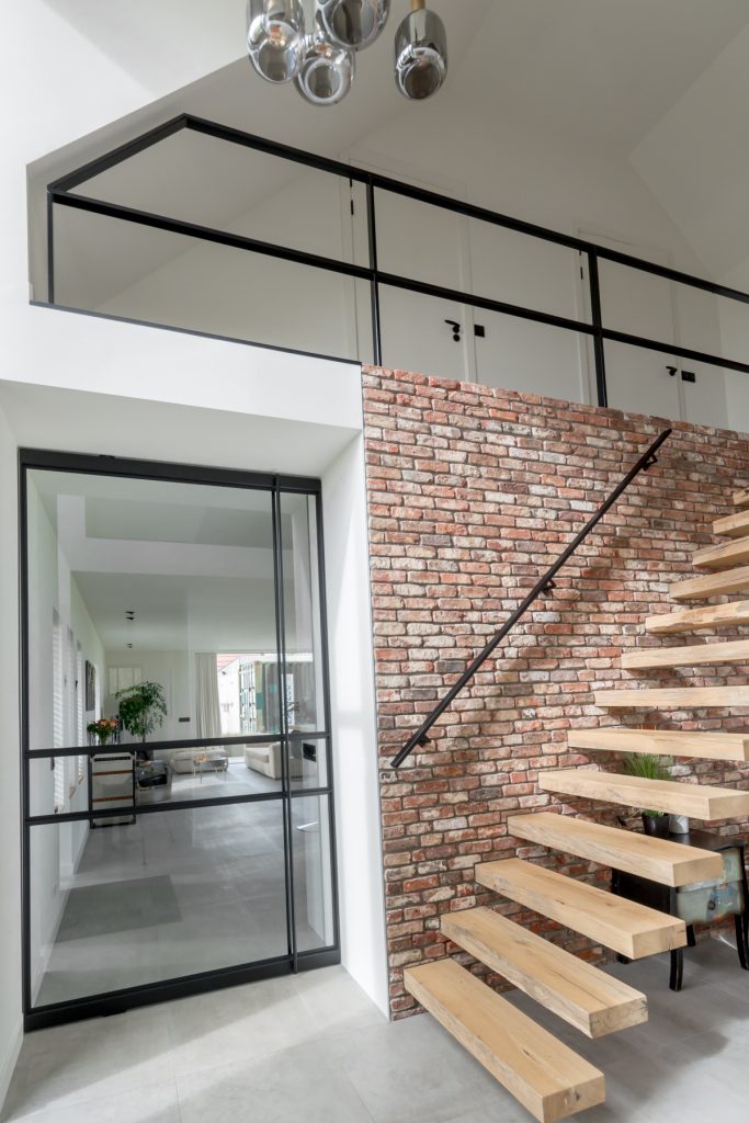 Industrieel interieur met stalen taatsdeur, trapleuning en balustrade uitgevoerd in RAL 9005 gitzwart.