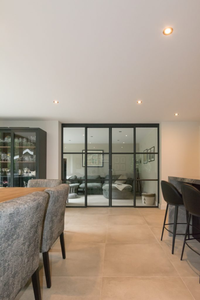 Stalen schuifpui als roomdivider tussen keuken en woonkamer.