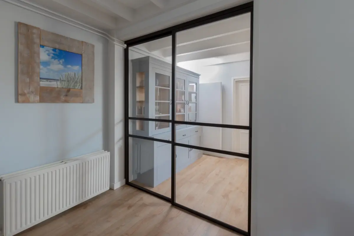 Stalen schuifdeur met raampaneel in landelijk modern interieur.