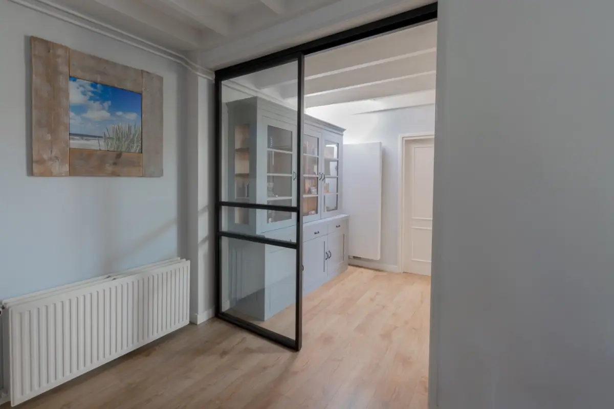 Stalen schuifdeur met raampaneel in landelijk modern interieur.