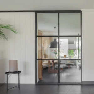 Minimalistisch interieur met zwart stalen schuifdeur tussen woonkamer en keuken.