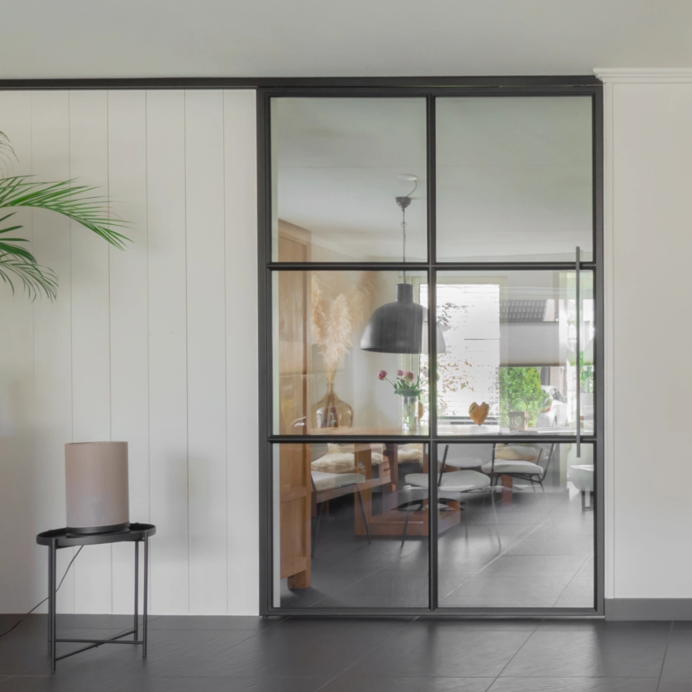 Project hoogkarspel: Minimalistisch interieur met zwart stalen schuifdeur tussen woonkamer en keuken.