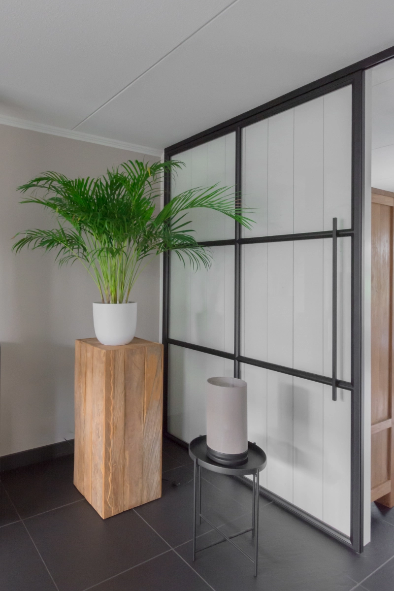 Minimalistisch interieur met zwart stalen schuifdeur tussen woonkamer en keuken.