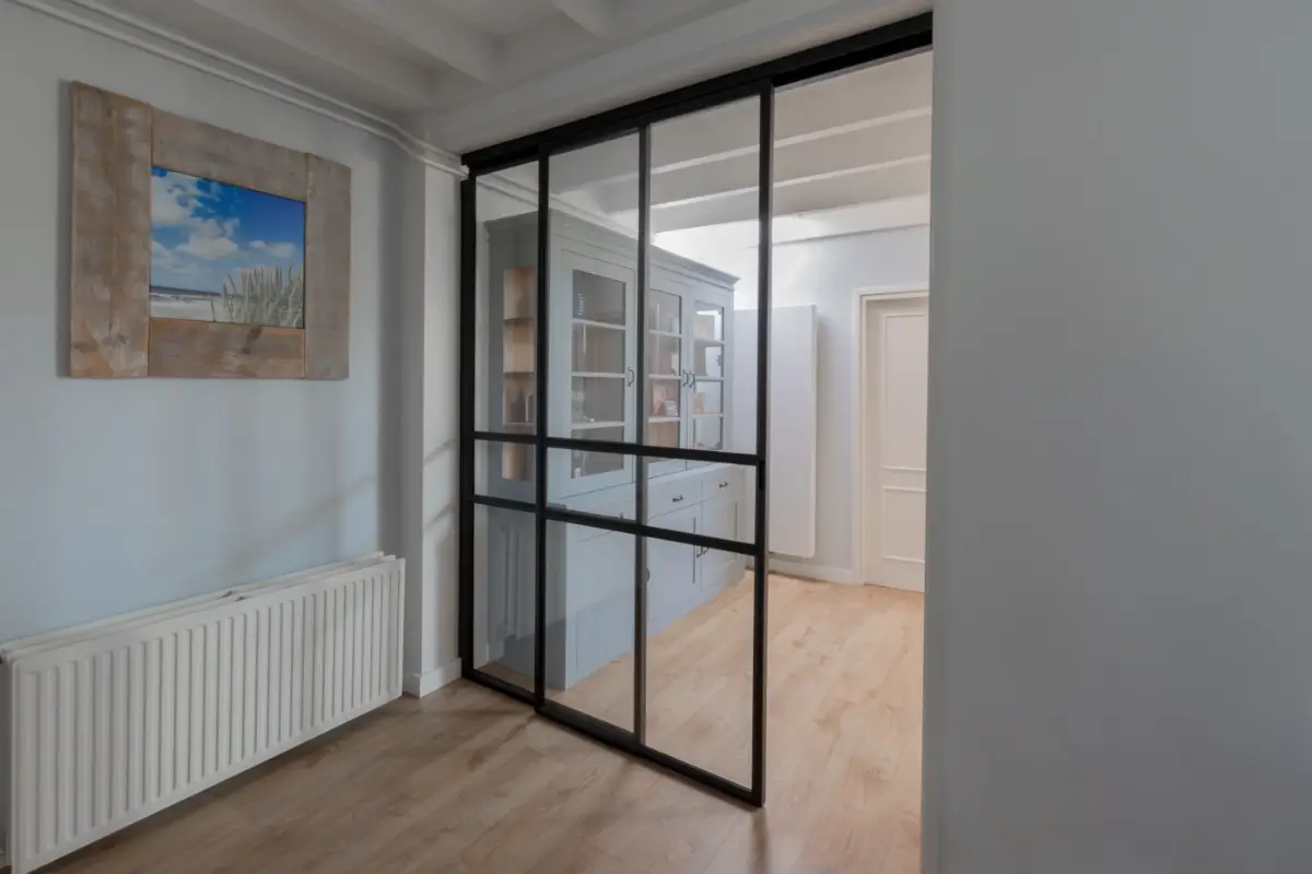 Stalen schuifdeur met raampaneel in landelijk modern interieur.