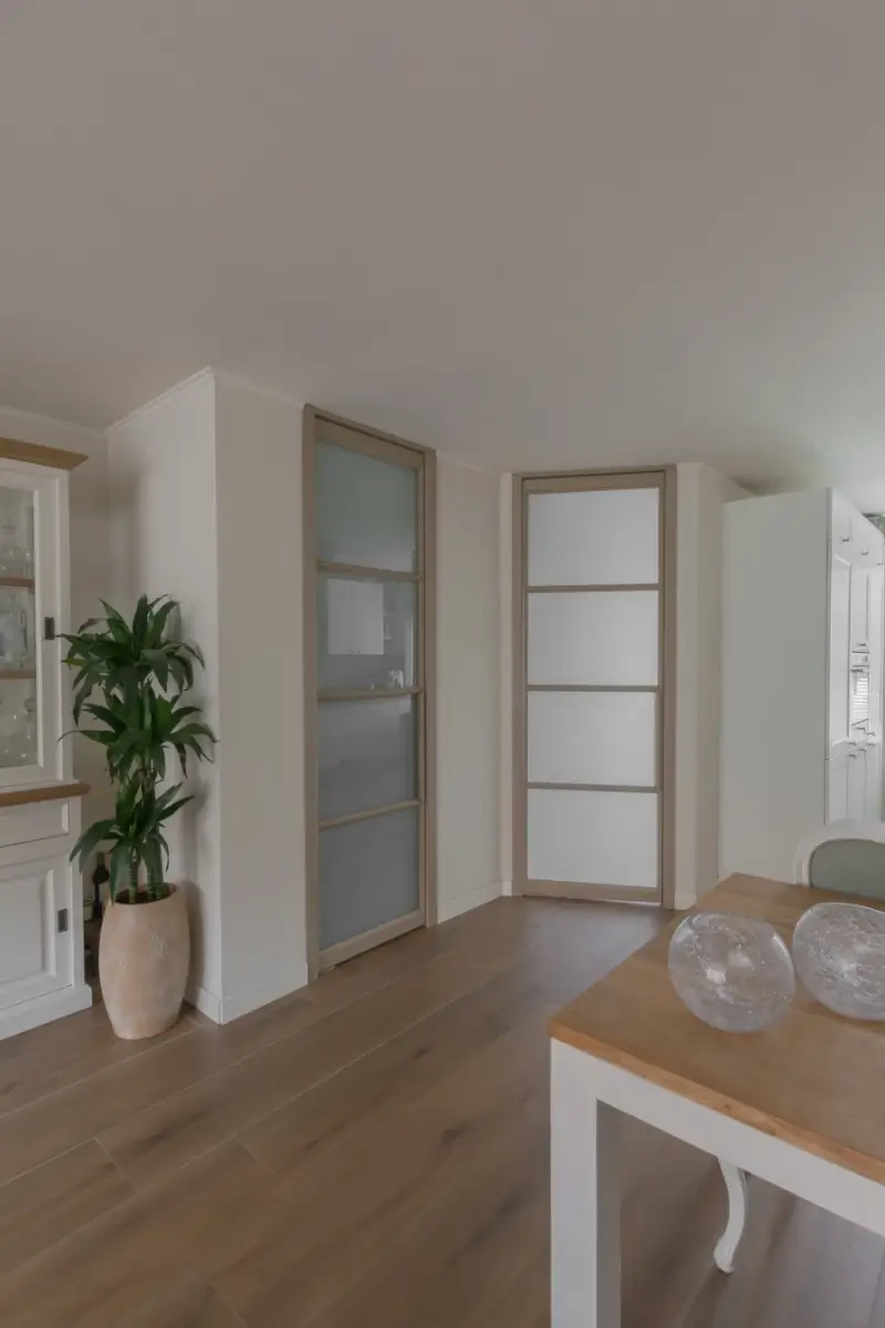Woonkamer met vernieuwd stalen kozijn en stalen taatsdeur voor trap.