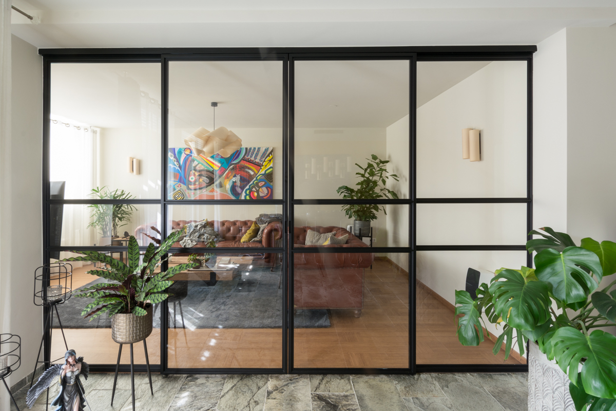 Stalen schuifpui met glas als roomdivider in moderne woonkamer