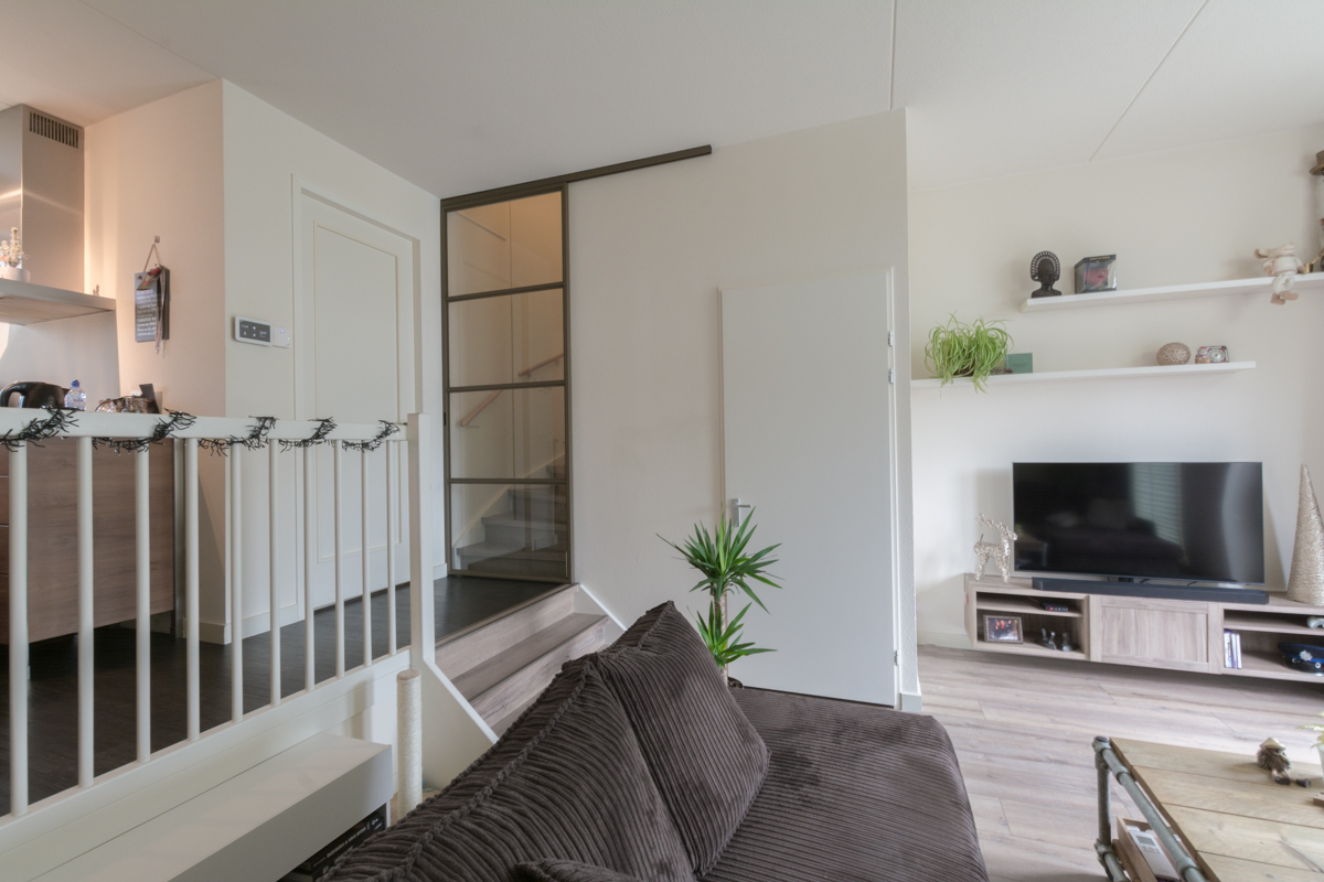 Split-level woning met stalen schuifdeur voor trap.