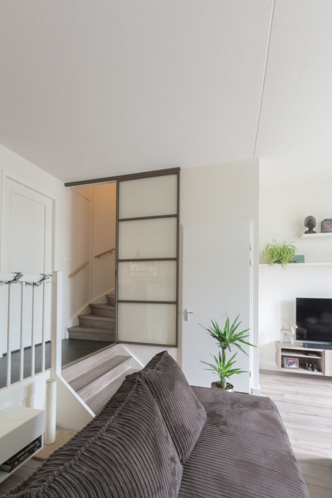 Split-level woning met stalen schuifdeur voor trap.