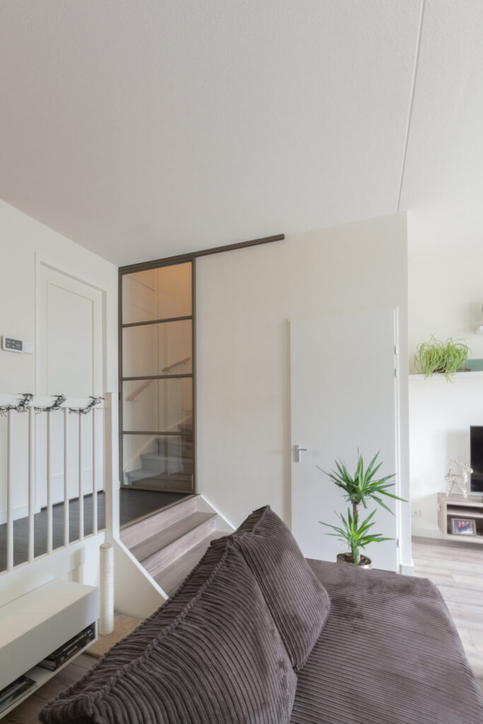 Split-level woning met stalen schuifdeur voor trap.