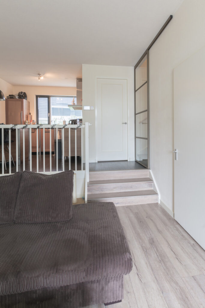 Split-level woning met stalen schuifdeur voor trap.