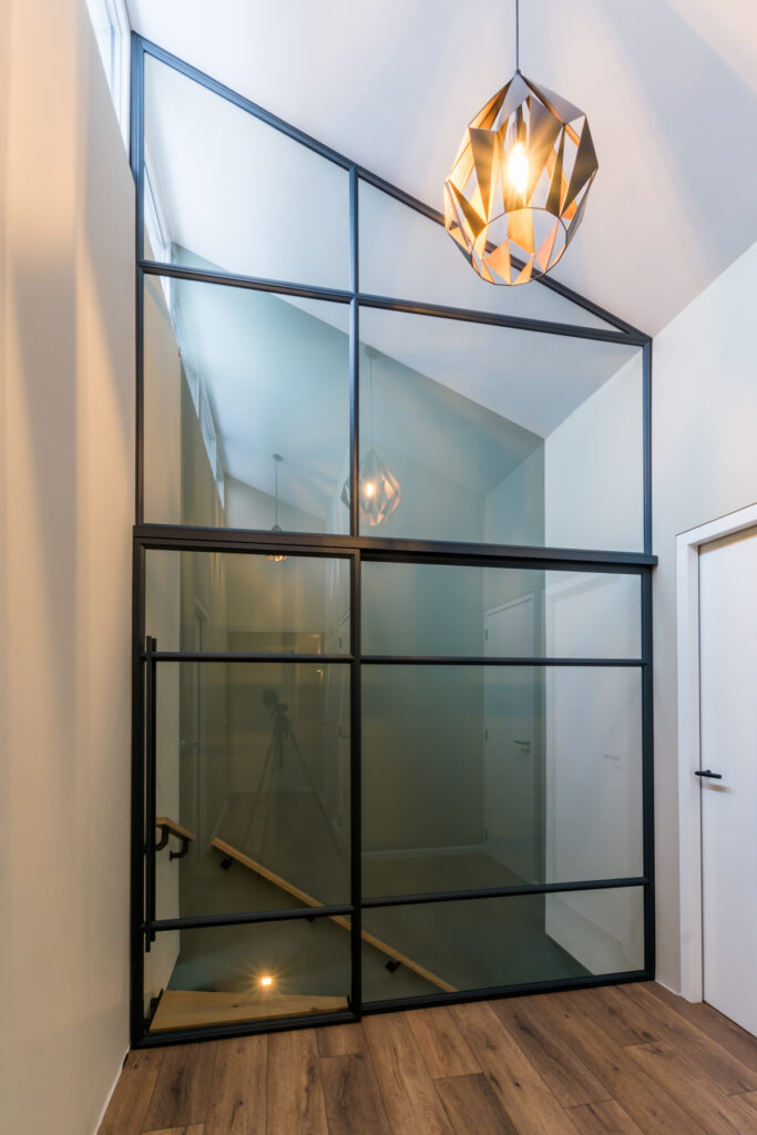 Stalen glazen pui met schuifdeur bij trap en schuin plafond