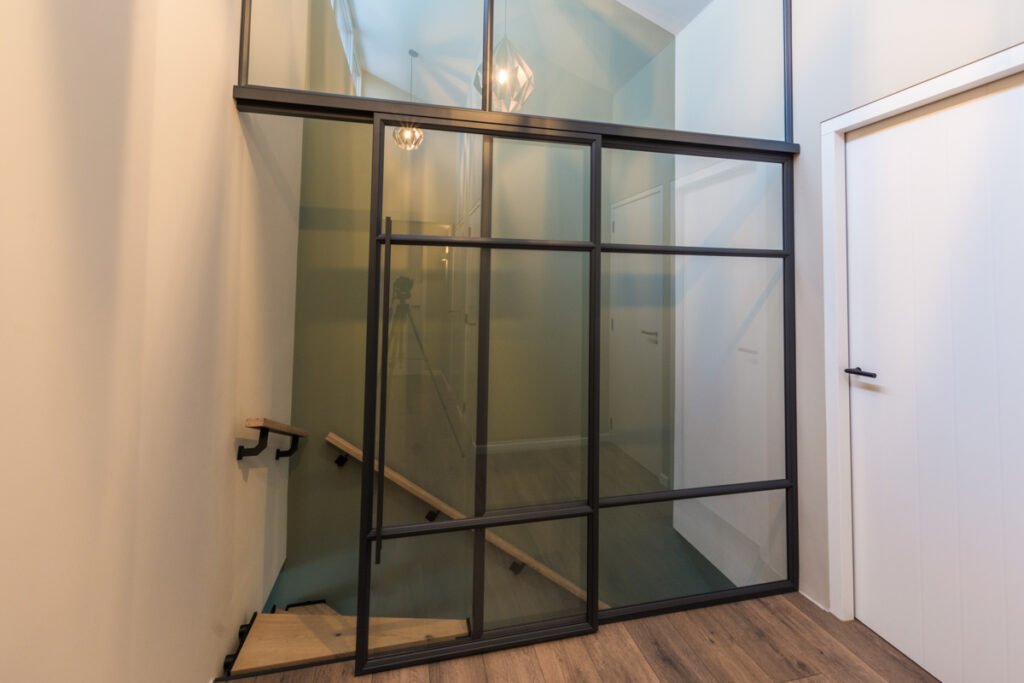 Stalen glazen pui met schuifdeur bij trap en schuin plafond