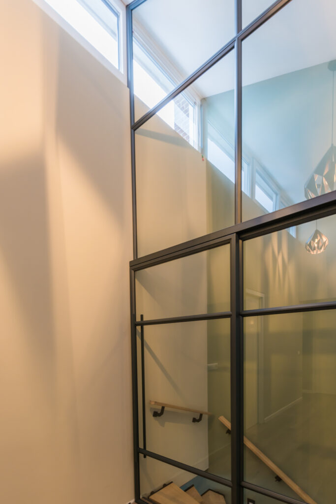 Stalen glazen pui met schuifdeur bij trap en schuin plafond