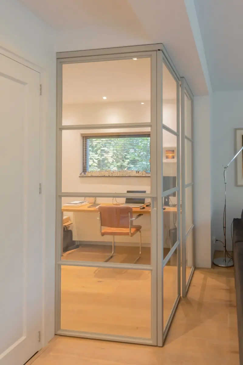Stalen schuifdeuren in hoekopstelling met raampaneel in moderne woonkamer.
