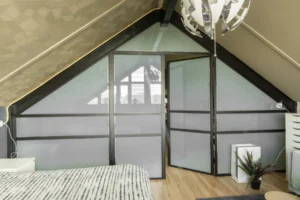 Stalen pui onder schuindak. op zolder slaapkamer met privacy glas.