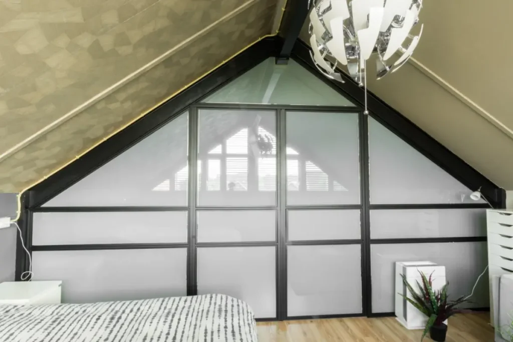 Stalen pui onder schuindak. op zolder slaapkamer met privacy glas.