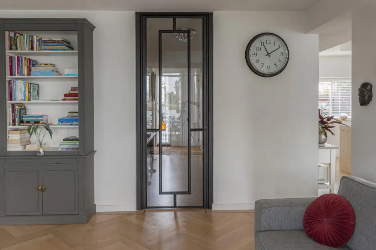 Stalen scharnierdeur met kozijnbekleding uitgevoerd in RAL 9005 gitzwart toegepast in een moderne leefruimte met doorkijk naar de hal.