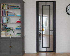 Stalen scharnierdeur met kozijnbekleding uitgevoerd in RAL 9005 gitzwart toegepast in een moderne leefruimte met doorkijk naar de hal.