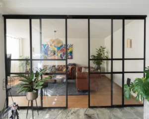 Stalen schuifpui met glas als roomdivider in moderne woonkamer