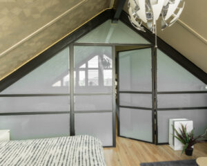 Stalen pui onder schuindak. op zolder slaapkamer met privacy glas.