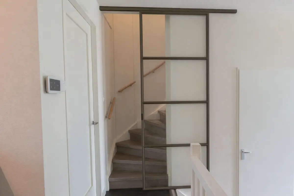 Stalen schuifdeur in splitlevel woning voor trap