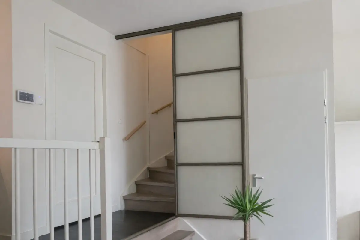 Stalen schuifdeur in splitlevel woning voor trap