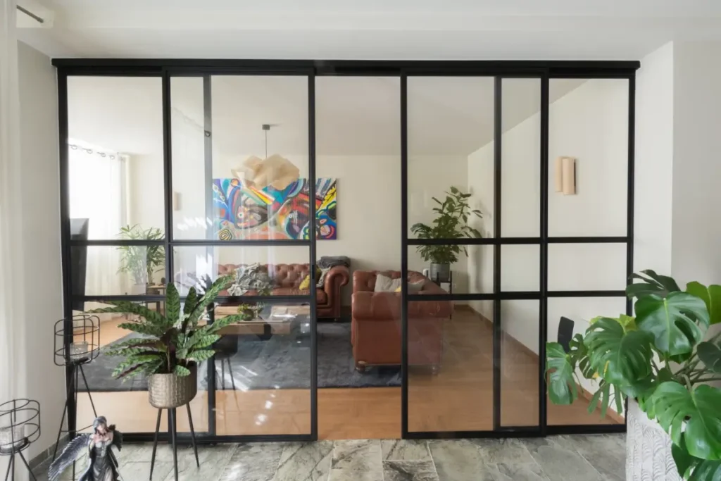 Stalen schuifpui met glas als roomdivider in moderne woonkamer