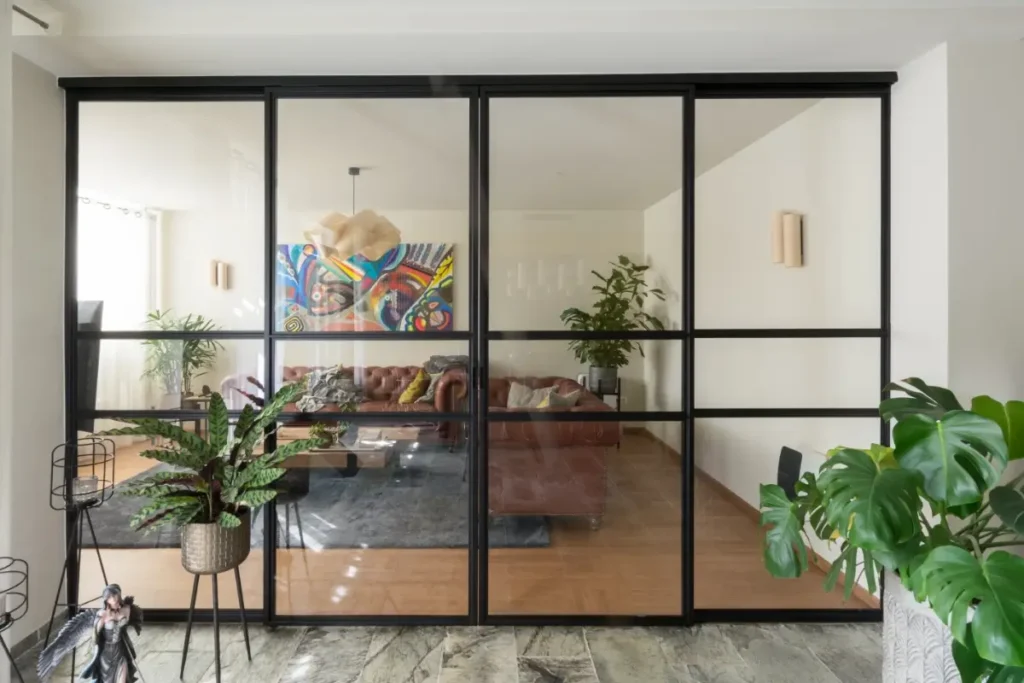 Stalen schuifpui met glas als roomdivider in moderne woonkamer
