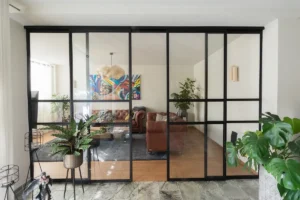 Stalen schuifpui met glas als roomdivider in moderne woonkamer