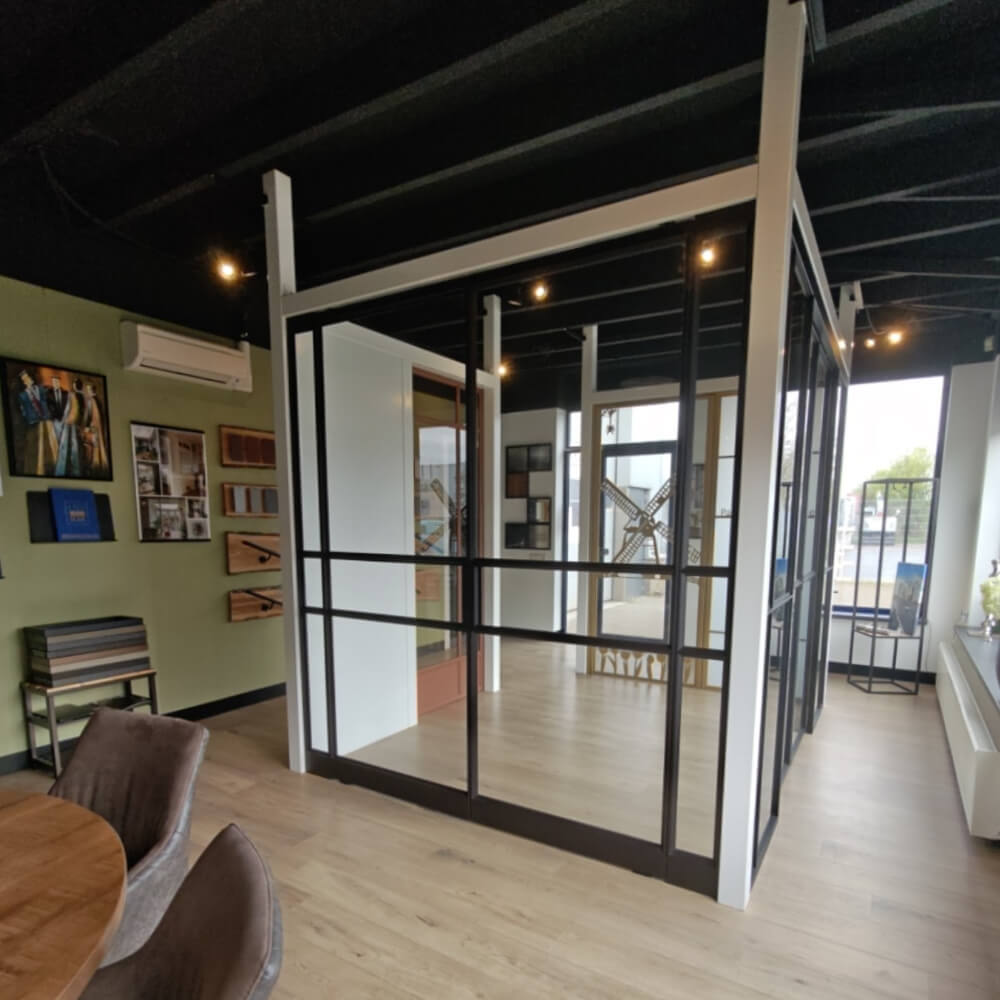 Showroom met stalen binnendeur in zwart staal, glazen wanden en licht houten vloer in moderne setting.