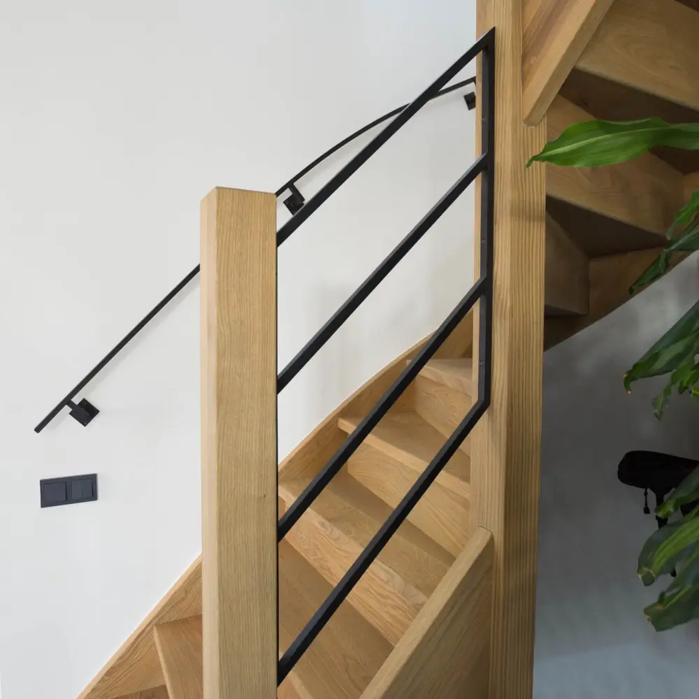Stalen trapleuning op maat langs een houten trap in modern interieur.